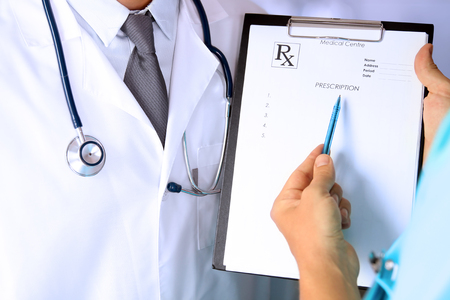medical doctor  with a stethoscope around his neck  showing prescription to the colleagueの写真素材