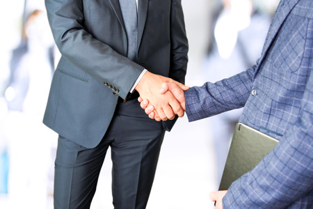 The Close-up image of a firm handshake between two colleagues in office.