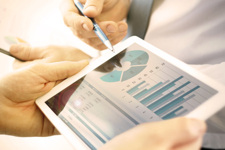 Business colleagues working and analyzing financial figures on a digital tabletの写真素材