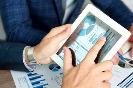 Business colleagues working and analyzing financial figures on a digital tabletの写真素材