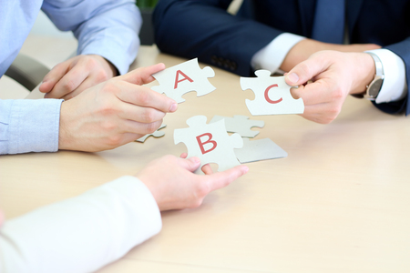 Close-up Of Businessmen Hand Connecting Jigsaw Puzzleの写真素材