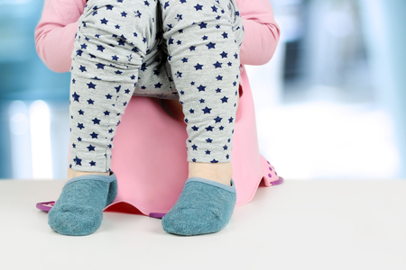 Children's legs hanging down from a chamber-pot on a blue backgroundの写真素材