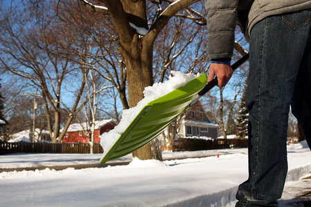 Man shoveling and removing snow in front of his house in the suburbの写真素材