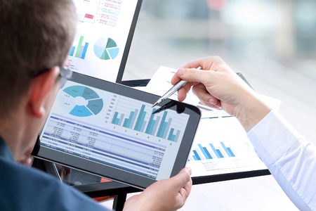 Business colleagues working and analyzing financial figures on a digital tabletの写真素材