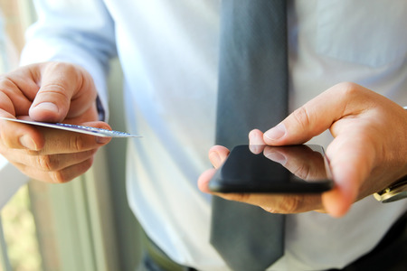 business man entering data of a credit card . On-line shopping on the internet using a mobile phoneの写真素材