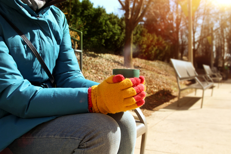 Cup of hot coffee warming in the hands of girl  outsideの写真素材
