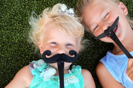 beautiful blonde smiling  girls  lying  on the grass on a summer day with mustacheの写真素材