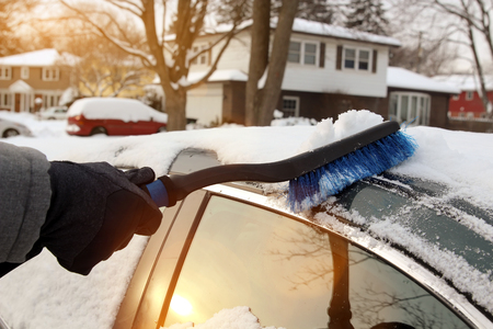 Transportation, winter  and vehicle concept - man cleaning snow from car with brush