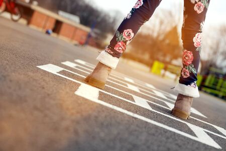 Girl in beautiful boots Playing Hopscotch On Playground Outdoorsの写真素材