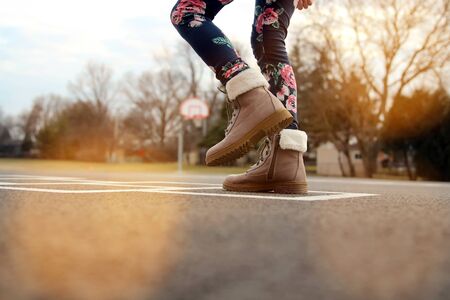 Girl in beautiful boots Playing Hopscotch On Playground Outdoorsの写真素材