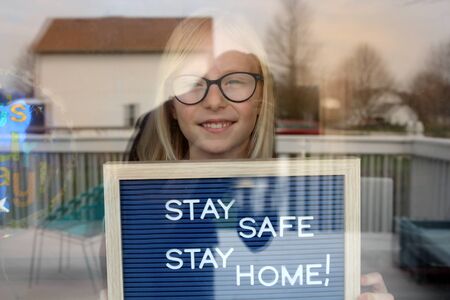 Stay home quarantine coronavirus pandemic prevention. Beautiful girl stays near the open windowの写真素材