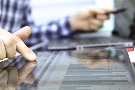Business man working and analyzing financial figures on a graphs using laptop and tablet