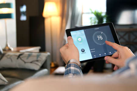 Man is Adjusting a  temperature using a tablet with smart home app in modern living roomの写真素材