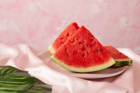 Three delicious pieces of watermelon on a pink plate, on a pink tablecloth on the table on a pink...