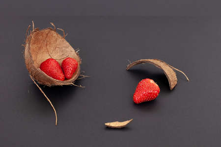 Red strawberries are in the coconut shell and on a black background, isolated.