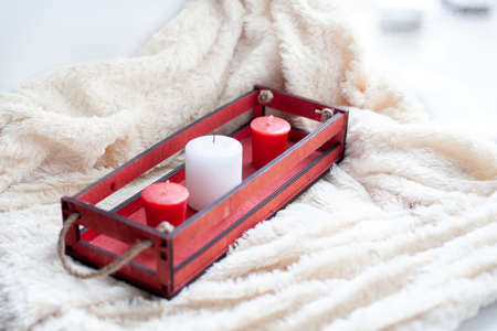 white, red candles, a red wooden box on a beige blanket.