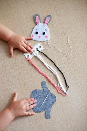 hands of a young girl close-up, she sews a macrame toy from thread.