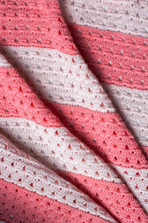 Pleats on fabric, knitted material of pink and white color, folds.