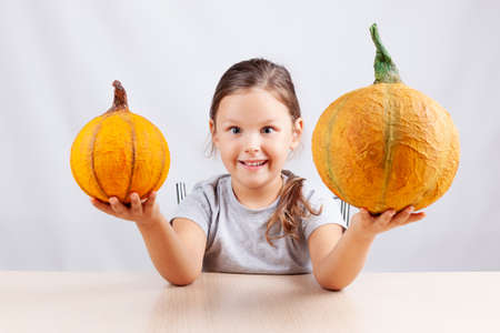 a happy child on a white background holds homemade papier-mache pumpkins for Halloweenの写真素材