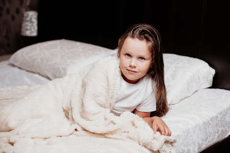 the girl just woke up, fresh beautiful morning face of a child in the bedroomの写真素材