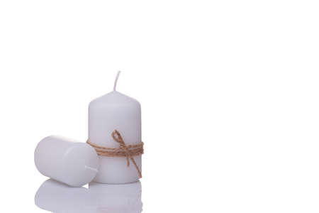 two white candles, one lying on the table, the other wrapped in jute rope, isolated