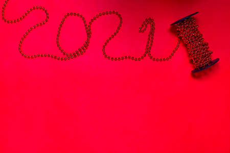 mock up of garlands of beads on spool for a new year tree in the form of the number 2021 on a red...