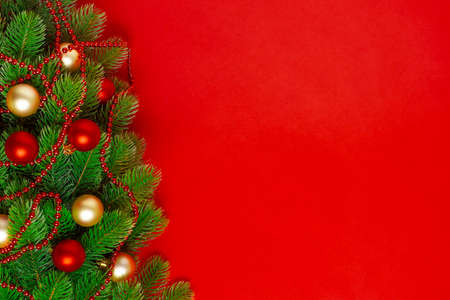 Christmas tree branches greeting card with red and Golden balls, a garland of beads on a rich...