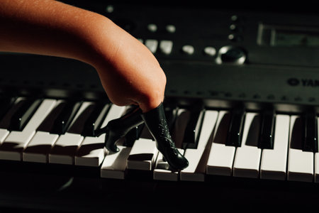 a childs hand with its fingers stuck in a toy dolls boot steps over the keys of a piano in a low key