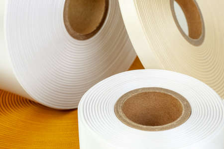 macro set of four coils of silk ribbons in white, beige, orange colors of different sizes for labels or branding, isolated on a white, gray backgroundの写真素材