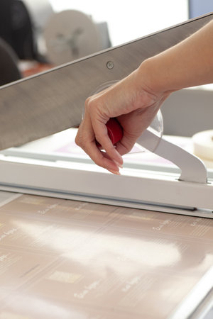 close-up a womans hand presses the handle of a manual guillotine for a machine in a printing house or factoryの写真素材