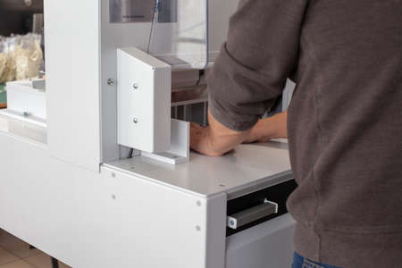 working operator works on automatic machine for cutting stack of papers or labels, a professional...