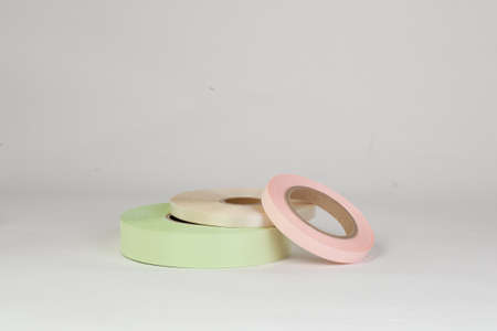 composition of three coils of satin ribbons in pink, green, beige for tags or branding, isolated on a white, gray backgroundの写真素材