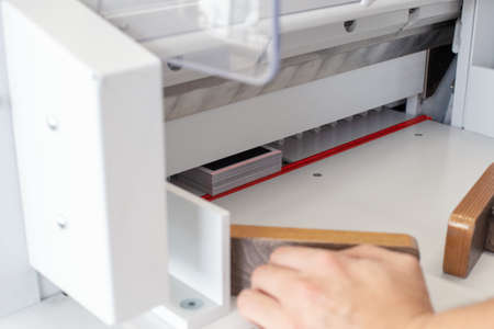 a specialist operator works on an automatic paper cutting machine, a professional cutter, equipment...
