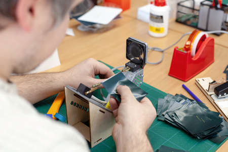 the worker sealing, cutting off edges of labels and tags for clothes on the electric string cutter...