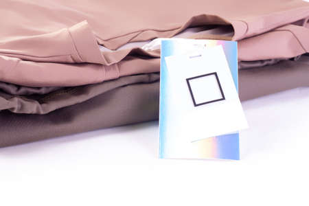 macro mock up empty paper metallic shiny iridescent label or tag on a stack of T shirts or hoodies