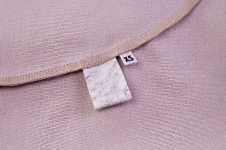 macro mock fabric blank white tag for clothing care instructions and tag with size XS sewn into the clothing seamの写真素材