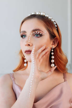 fashion close-up portrait of a beautiful woman with pearl beads makeup on her face and handの写真素材