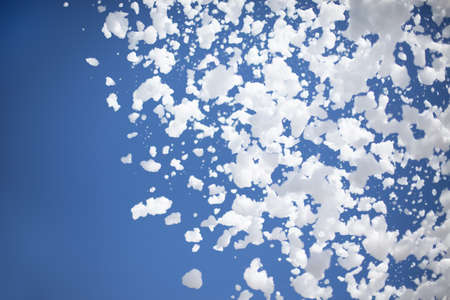 foam flakes from a foam pool party on the background of a blue summer sunny clear sky with copy...