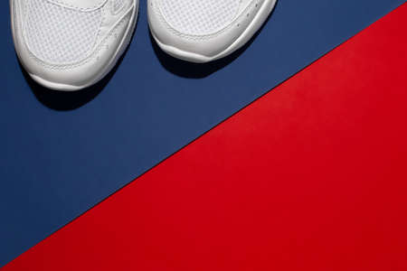 flat lay front part of white sneakers with hard summer shadows on a modern background with a...