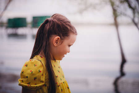 close-up portrait of a smiling girl with long hair and a beautiful hairstyle with the surface of a river, water or lake on the backgroundの写真素材