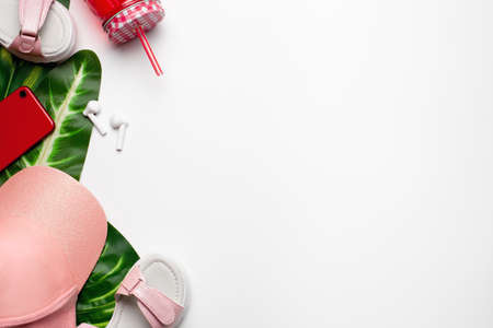 Beach fashion girls accessories on white background with palm green leaves. Flat lay, top view