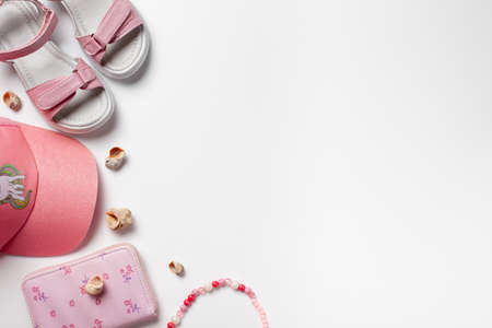 Flat lay with summer accessories. Girls accessories, pink sandals and cap on the white isolated background with copy spaceの写真素材