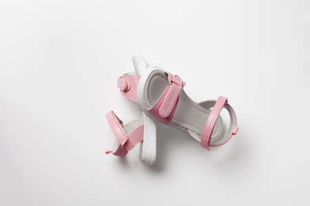 Pink childrens sandals made of shiny leather with  fasteners, flat white soles isolated on a white background. A pair of fashionable childrens sandals for a comfortable walk.の写真素材