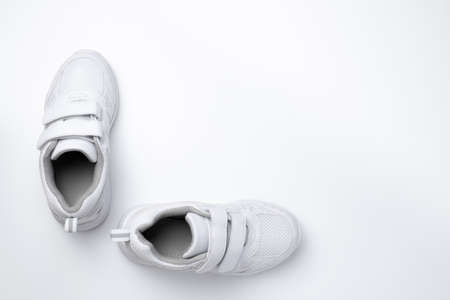 flat lay two white unisex sneakers with fasteners at a 90 degree angle to each other isolated on a white backgroundの写真素材