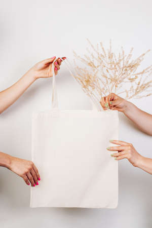 Female hands hold reusable eco-bag. Mocku of cotton white bag on white isolated background with...