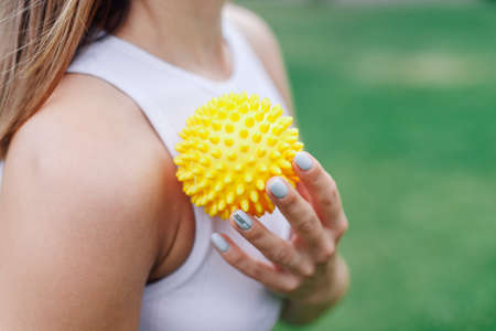 spiky rubber massage ball for muscle recovery in hands of young woman after workout in parkの写真素材