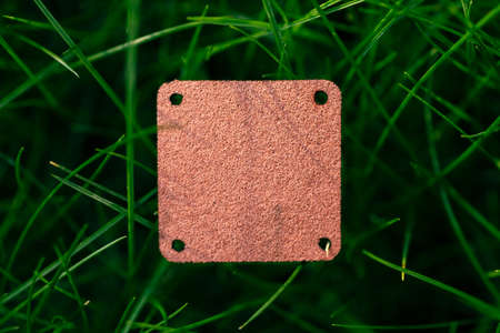 Top view of square brown leather patch for clothing creative layout of lawn green grass with tagの写真素材