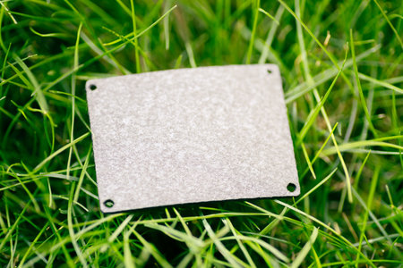 Top view of square gray leather patch for clothing creative layout of lawn green grass with tagの写真素材