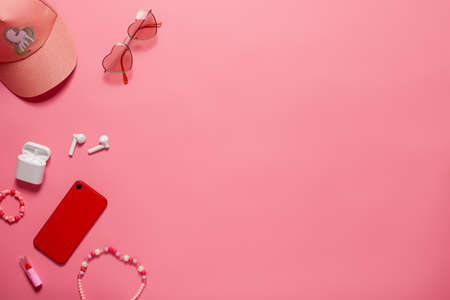 Top view with phone accessories and baseball cap. Phone and accessories with copy space on the pink...
