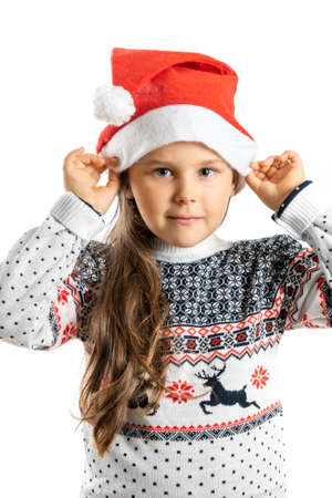 portrait of charming girl in white knitted Christmas sweater with reindeer holding Santa Claus hat, isolated on white backgroundの写真素材